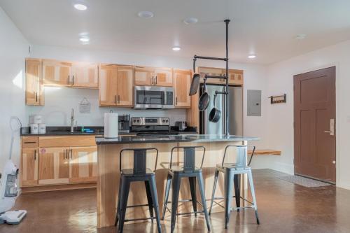 a kitchen with wooden cabinets and a counter with three bar stools at The Pet Friendly Executive Northernwind Suite 1.0 in Fairbanks