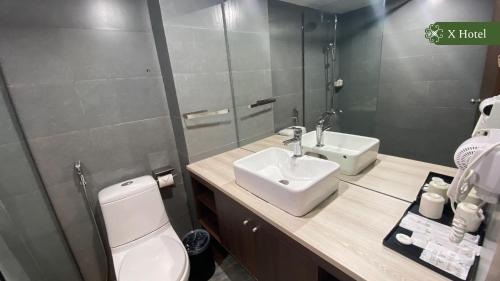 a bathroom with a sink and a toilet and a mirror at X Hotel Thái Nguyên in Thái Nguyên