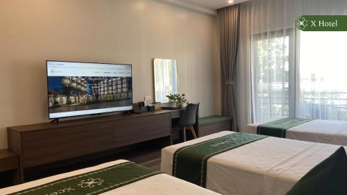 a hotel room with two beds and a flat screen tv at X Hotel Thái Nguyên in Thái Nguyên