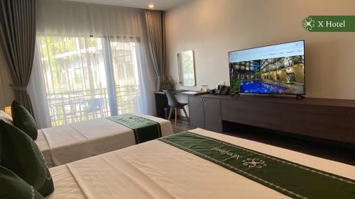 a hotel room with two beds and a flat screen tv at X Hotel Thái Nguyên in Thái Nguyên