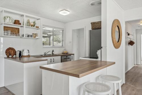 a kitchen with white cabinets and a wooden counter top at Percys Place- Waterfront pet and family friendly in Goolwa