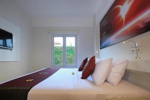 登巴薩的住宿－Mars City Hotel，卧室配有带红色枕头的大型白色床
