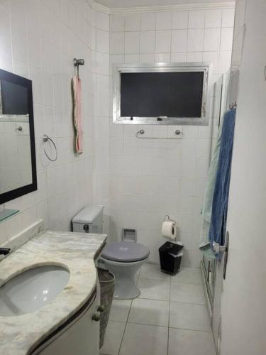a white bathroom with a sink and a toilet at Casa Tomazella in Guarujá