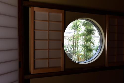 a round window in a room with a tree at Ubusuna no Sato TOMIMOTO in Ando