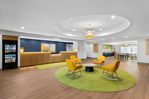 a waiting room with yellow chairs and a table at Spark By Hilton Missouri City in Missouri City
