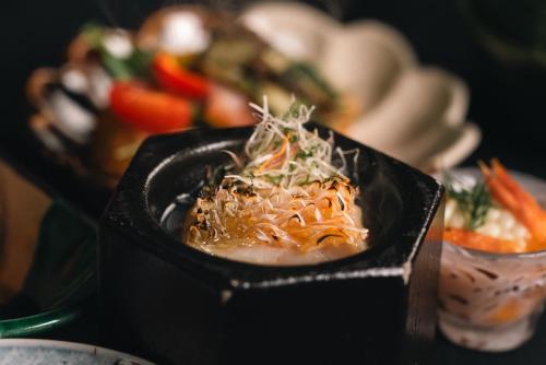 a black bowl of food on a table with vegetables at Boscage Kariya in Yugawara