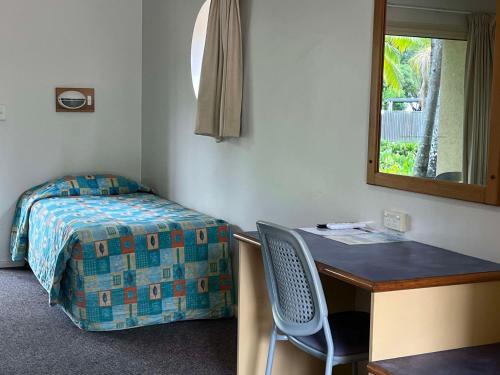 a bedroom with a desk and a bed and a mirror at Bushland Beach Tavern in Townsville