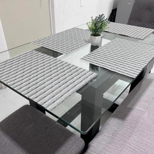 a glass table with benches and a potted plant on it at Bonito departamento en privada con alberca in Cancún