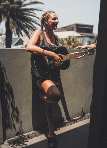 a woman is playing a guitar on a ledge at Boardrider Backpackers and Budget Motel in Sydney