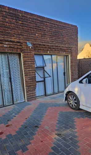 クラークスドープにあるHappy stay guest house in klerksdorp North Westのレンガ造りの建物の前に駐車した白車