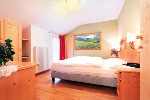 a bedroom with a bed and a window at Hotel Bellevue in Canazei
