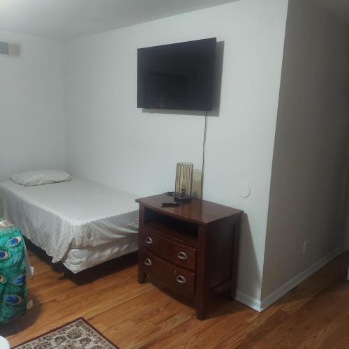 a bedroom with a bed and a dresser with a tv on the wall at Cosy Bedroom 12mins to Airport Prudential NJIT UMDJ Penn Station in Newark