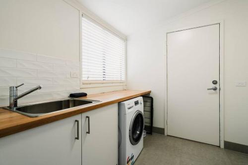 a kitchen with a sink and a washing machine at 50m Walk to River , Pet Friendly, Spacious in Ocean Grove