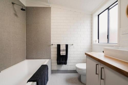 a bathroom with a tub and a toilet and a sink at 50m Walk to River , Pet Friendly, Spacious in Ocean Grove
