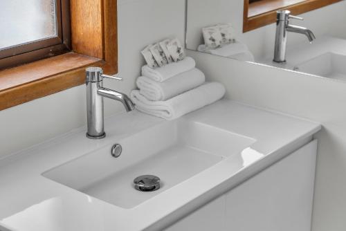 a bathroom sink with two faucets and towels at Harbour Lights - townside with a pool in Merimbula