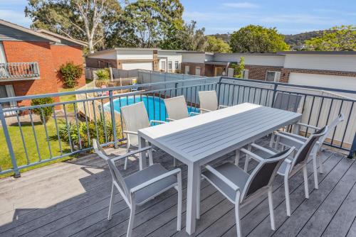 a wooden deck with a table and chairs at Harbour Lights - townside with a pool in Merimbula