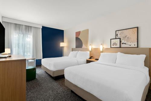 a hotel room with two beds and a television at Spark By Hilton Missouri City in Missouri City