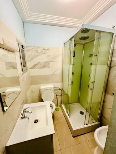 a bathroom with a sink and a shower and a toilet at Villa Amina in Ouagadougou