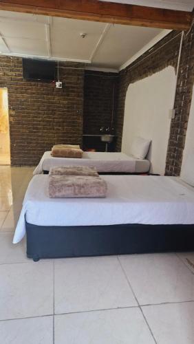 three beds in a room with towels on them at Goodlife Guest house in mafikeng in Mahikeng