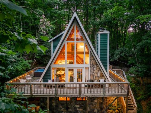 a house in the woods with a large window at Big Mountain View! Downtown Gatlinburg Chalet Village! Hot Tub! Fan Favorite! AFrame Dreams! Magazine-Featured! Stunning Interiors! Little Green Cabin in Gatlinburg