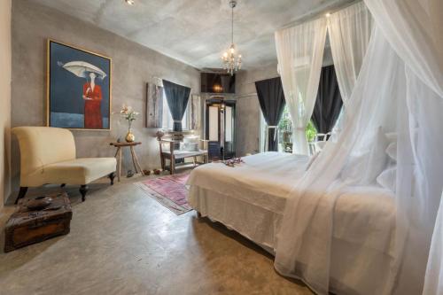 a bedroom with a white bed and a chair at Aruma Villa Boutique Isla Mujeres with beach club access included in Isla Mujeres