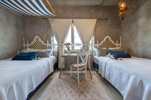 a bedroom with two beds and a table with a chair at Aruma Villa Boutique Isla Mujeres with beach club access included in Isla Mujeres