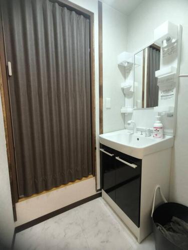 a bathroom with a shower with a sink and a mirror at INN Kumihama 丹後 一棟貸し 海の宿 INN久美浜 in Kyotango