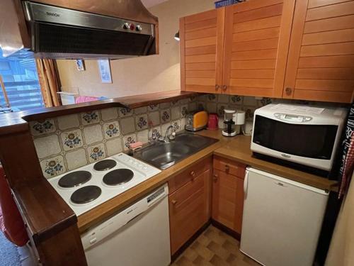 une cuisine avec une cuisinière, un évier et un micro-ondes dans l'établissement Appartement cosy avec balcon au cœur de la station - FR-1-787-78, à Laveissière