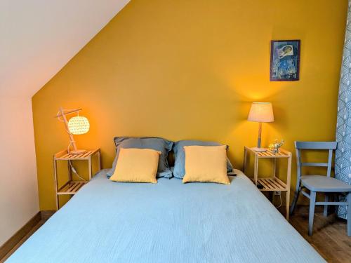 a bedroom with a blue bed with a yellow wall at Deux maisons berrichonnes avec jardin privatif et cour partagée, idéale pour les groupes - FR-1-591-617 in Thenay