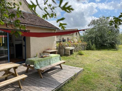 a table and benches on a wooden deck next to a house at Deux maisons berrichonnes avec jardin privatif et cour partagée, idéale pour les groupes - FR-1-591-617 in Thenay