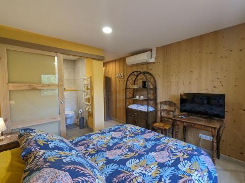 une chambre avec un lit, un bureau et une télévision dans l'établissement Chambre climatisée avec salle d'eau privative et accès jardin - FR-1-589-664, à Rehaupal