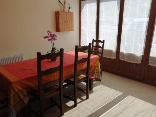 une table à manger avec deux chaises et un vase avec des fleurs. dans l'établissement Charmante Chambre Myosotis avec Jardin et DVD - FR-1-589-665, à Rehaupal