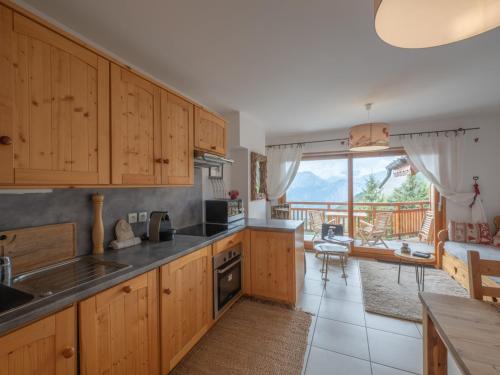 une cuisine avec des placards en bois et une vue sur un balcon. dans l'établissement Chalet Savoyard pour Familles - Centre Huez - FR-1-645-76, à Huez