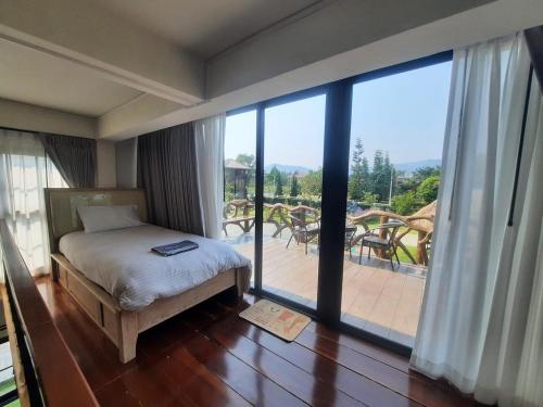 a bedroom with a bed and a large glass window at Kataipakhaoyai in Ban Tha Chang