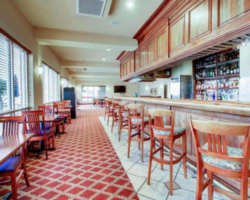 a restaurant with a bar with wooden tables and chairs at Clarion Suites Vidalia Riverfront in Vidalia