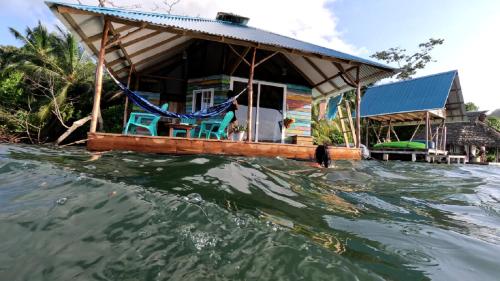 a house on a boat in the water at El Toucan Loco Floating Lodges in Tierra Oscura
