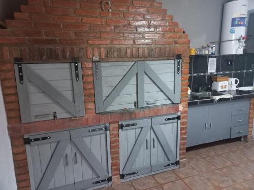 Una cocina con puertas grises y una pared de ladrillo. en El Cardiel, en Gobernador Gregores