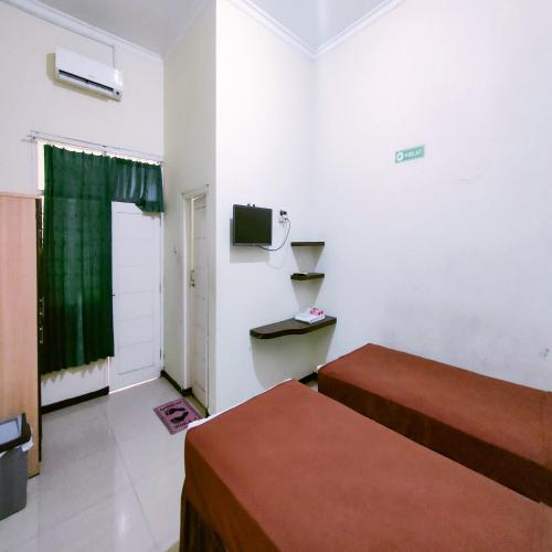 a hotel room with two beds and a television at Djati Homestay Redpartner near Gor Djarum Kudus in Kudus