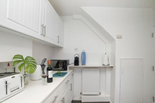 a white kitchen with white cabinets and a sink at Wilson House - Camden in London