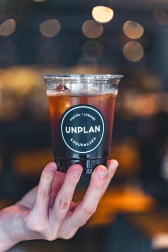 a person holding up a plastic cup with a drink at UNPLAN Kagurazaka in Tokyo