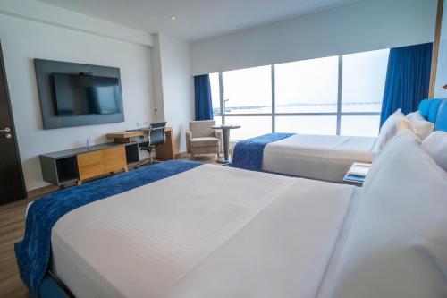 a hotel room with two beds and a flat screen tv at Wyndham Guayaquil, Puerto Santa Ana in Guayaquil