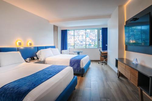 a hotel room with two beds and a flat screen tv at Wyndham Guayaquil, Puerto Santa Ana in Guayaquil