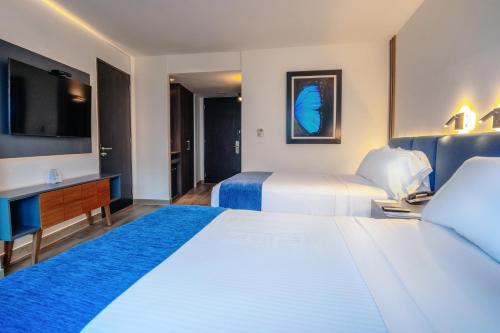 a hotel room with two beds and a tv at Wyndham Guayaquil, Puerto Santa Ana in Guayaquil
