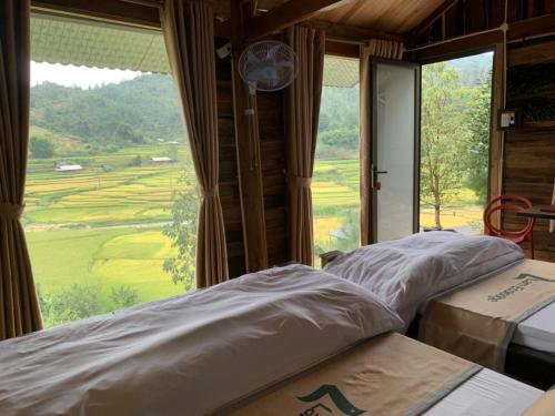 two beds in a room with a large window at Lam Ecolodge Mu Cang Chai in Nam Khat