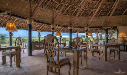 a dining room with tables and chairs and a view at Mara Major Camp in Masai Mara