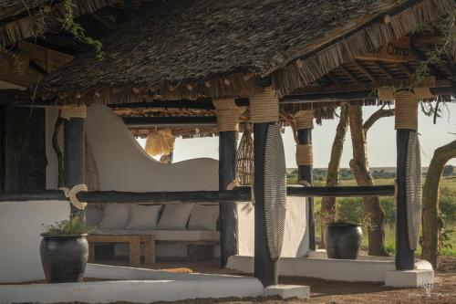 a pavilion with a chair and a table and trees at Mara Major Camp in Masai Mara