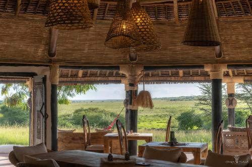 a restaurant with tables and chairs and large windows at Mara Major Camp in Masai Mara