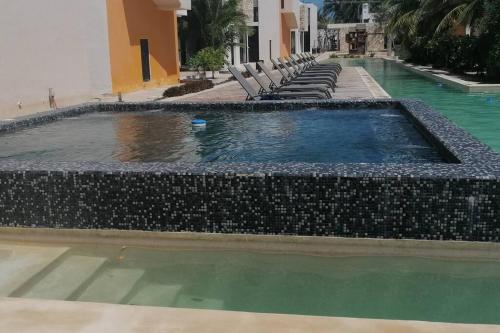 a swimming pool with a row of chairs next to a building at Villa Nicte ha - Antalea in Telchac Puerto