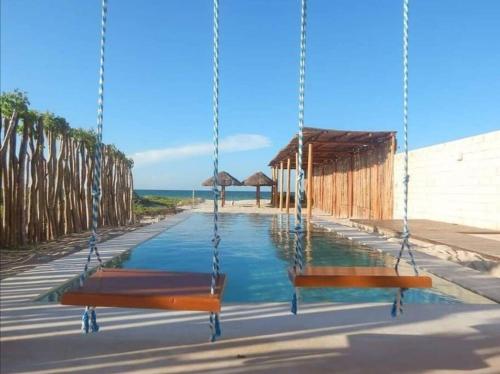 a swing with a pool of water at Villa Nicte ha - Antalea in Telchac Puerto