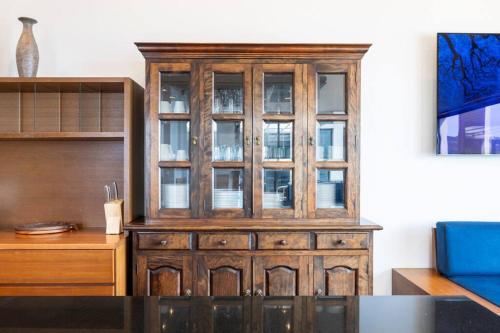 a wooden cabinet with glass doors in a living room at 野辺崎の風 Nobezaki no kaze in Itoshima